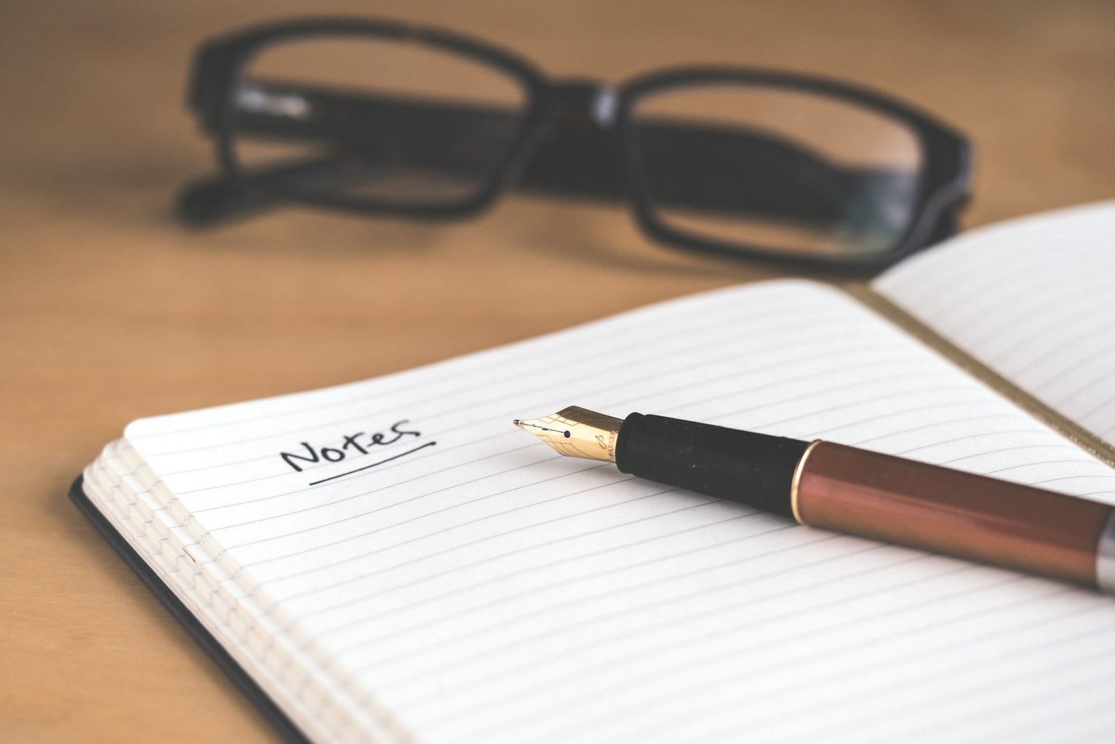 Open notebook with a pen on a wooden desk in soft morning light